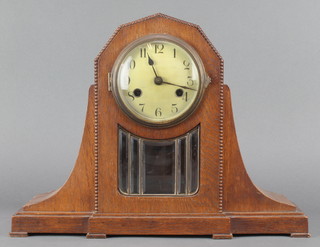 An Edwardian striking mantel clock with silvered dial and Arabic numerals contained in an oak and glass case 