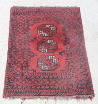 A red ground Afghan rug with 3 octagons to the centre 58" x 40", some wear and light staining 