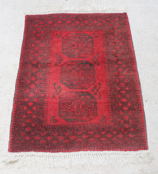 A red ground Afghan rug with 3 octagons to the centre within a multi-row border, in wear 61" x 41 1/2" 