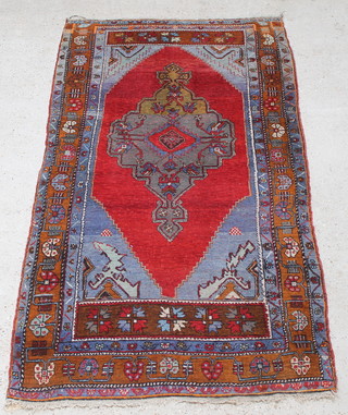 A Turkish Milas orange and blue ground rug with medallion to the centre 91" x 48", worn 