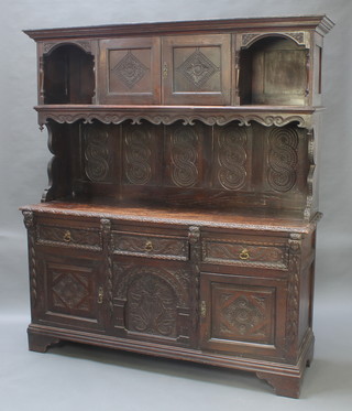 A Victorian heavily carved dark oak dresser, the upper section with moulded cornice and cupboard flanked by a pair of niches above a recess, the base fitted 3 long drawers above double cupboard 78 1/2"h x 67"w x 20 1/2"d 