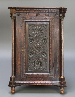 A Victorian carved oak hanging corner cabinet with moulded cornice, columns to the side with brass Corinthian capitals, fitted shelves enclosed by a panelled door 33"h x 23"w x 16 1/2"d 
