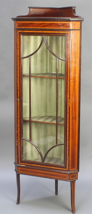 An Edwardian inlaid mahogany corner cabinet, the upper section with raised back fitted shelves enclosed by astragal glazed panelled doors, raised on out swept supports 63"h x 23"w x 15"d 