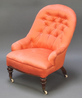 A Victorian iron framed nursing chair upholstered in buttoned orange material raised on turned supports 