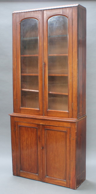 A Victorian mahogany bookcase on cabinet enclosed by arched glazed panelled doors, the lower section enclosed by a double cupboard 92"h x 40" x 15 1/2" 