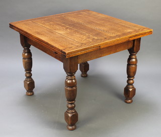 A square oak draw leaf dining table raised on turned supports 29 1/2"h x 36" square