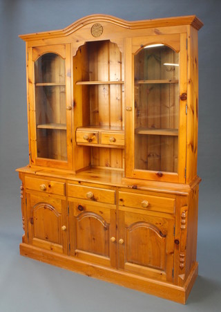 A pine dresser, the upper section fitted shelving above 2 short drawers flanked by glazed panelled doors, the base fitted 3 long drawers above cupboards, raised on a platform base 81"h x 60"w x 16"d 