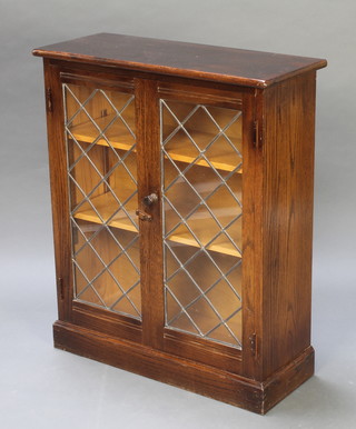 An oak bookcase enclosed by astragal glazed doors raised on a platform base 34"h x 28 1/2"w x 11"d 