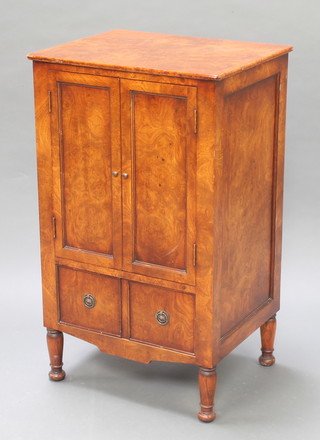 A walnut cabinet enclosed by panelled doors above 1 long drawer raised on turned supports 34" x 20 1/2" x 16" 