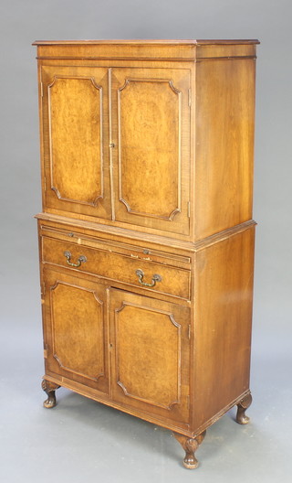 A walnut cocktail cabinet, the upper section enclosed by panelled doors the base with brushing slide, 1 long drawer and a double cupboard, raised on cabriole supports 58 1/2"h x 29 1/2"w x 16"d 