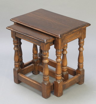 A rectangular oak nest of 2 interfitting coffee tables raised on turned supports 