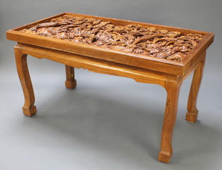 A rectangular hard wood dining table with heavily carved top depicting elephants in a jungle, raised on out swept supports 32"h x 59"w x 31 1/2d (there is no glass top to this table)