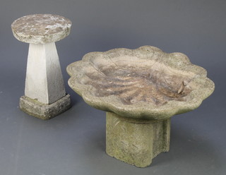 A concrete garden bird bath in the form of a shell together with a small concrete staddle stone