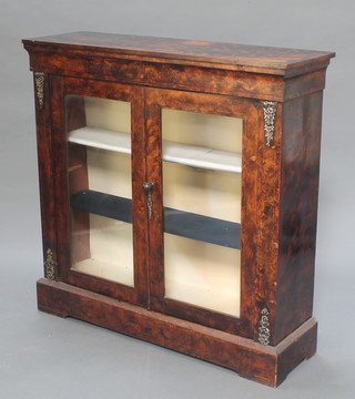A Victorian mahogany cabinet with metal mounts, enclosed by glazed panelled doors and raised on a platform base