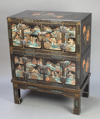 A chinoiserie style black lacquered cabinet enclosed by panelled doors raised on square supports 40"h x 31"w x 18"d 