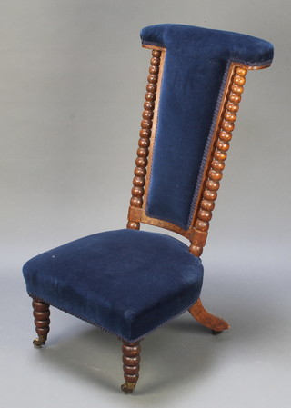 A Victorian oak framed Prie Dieu chair upholstered in blue with bobbin turned columns to the side, raised on bobbin turned supports 