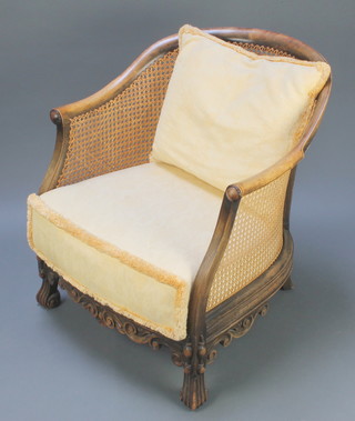 An Edwardian mahogany framed tub back single cane bergere armchair, raised on scrolled supports with roundel decoration to the arms 