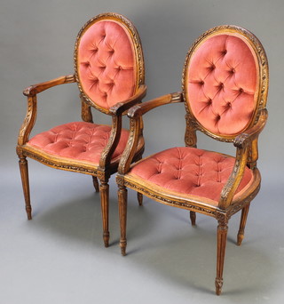 A pair of 19th Century carved walnut open arm salon chairs upholstered in pink buttoned material on turned and fluted supports 