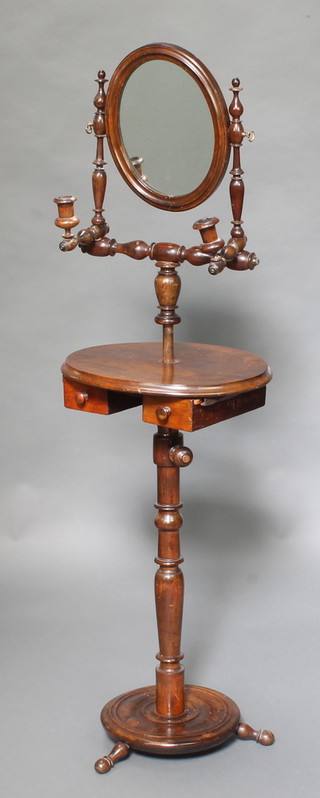 A 19th Century mahogany shaving stand fitted an oval plate mirror and pair of candle sconces, the oval adjustable base fitted 2 drawers raised on turned supports 31"h x 16 1/2"w x 13 1/2"d 
