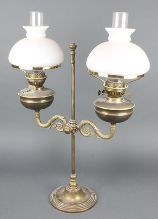 A 19th Century gilt metal adjustable brass twin light oil lamp with clear glass shade, converted to electricity 