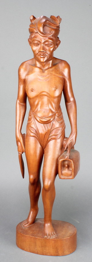 A Balinese carved hardwood figure of a standing gentleman 24" raised on an oval base (split to body) 
