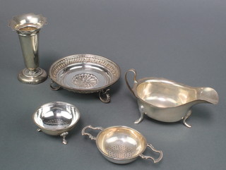 A silver sauce boat with cut rim on pad feet Sheffield 1964, a repousse bowl and a tea strainer on stand together with a spill vase 100 grams 