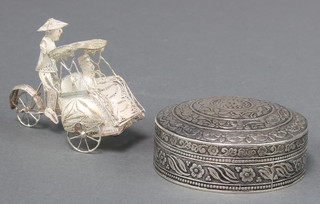 A Persian circular silver box with floral decoration and a filigree figure of a gentleman riding a rickshaw, 98 grams