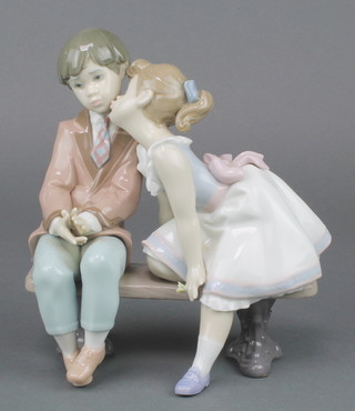 A Lladro figure of a boy and girl sitting on a bench 7635 8" 