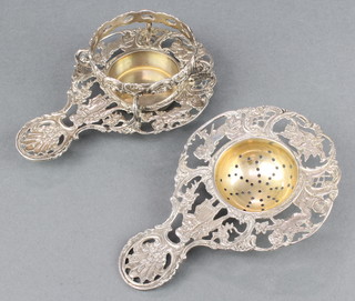 A Continental silver tea strainer and stand with pierced scroll figures and cherubs 152 grams 