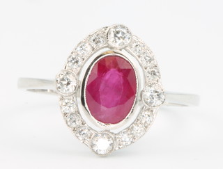 An 18ct white gold oval ruby and diamond cluster ring, size O 1/2