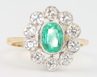 An 18ct yellow gold emerald and diamond oval cluster ring, the centre stone approx. 0.5ct surrounded by 10 brilliant cut diamonds,  size N 1/2
