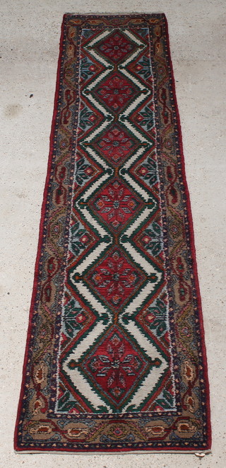 A Persian red, white and green runner with 6 stylised diamonds to the centre within a multi row border 128"l x 31"w
