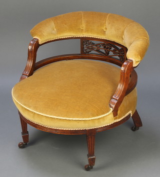 A Victorian mahogany tub back chair upholstered in mustard material, raised on fluted supports