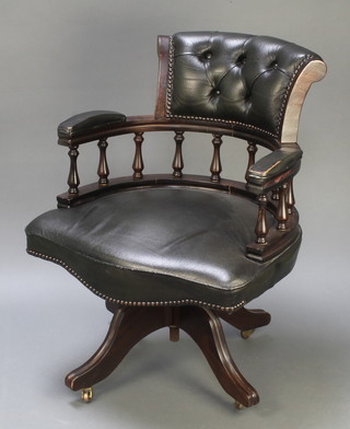 A mahogany revolving office chair upholstered in green "leather" material 