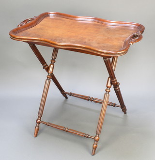 A 19th Century shaped mahogany twin handled tea tray with bracketed border, raised on an associated folding stand 29"h x 30"w x 20 1/2"d 