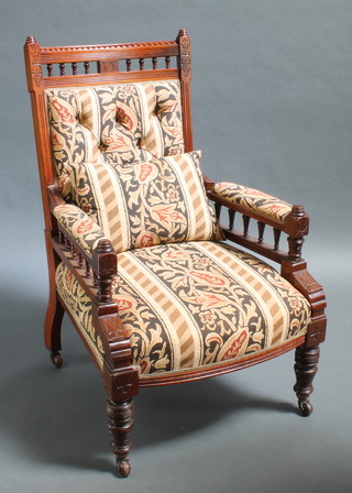 A Victorian carved walnut show frame armchair with bobbin turned decoration upholstered in striped material, raised on turned supports 