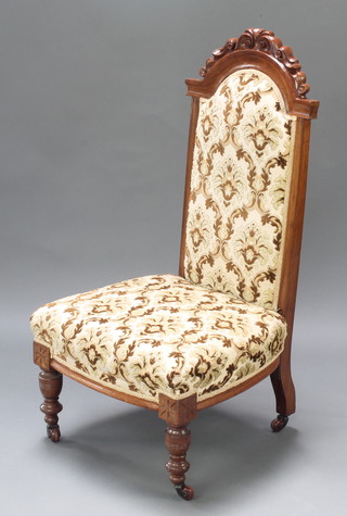 A Victorian walnut show frame nursing chair raised on turned supports