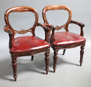 A pair of Victorian style mahogany balloon back carver chairs with carved mid rails, the seats of serpentine outline, raised on cabriole supports 
