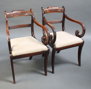 A pair of Regency mahogany and brass inlaid bar back carver chairs with upholstered drop in seats raised on sabre supports 