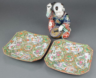 A 20th Century Chinese figure of a seated boy beating a drum 7 1/2" together with a pair of octagonal Cantonese plates decorated with figures 8 1/2" 