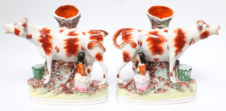 A pair of Victorian Staffordshire spill vases in the form of a cow and milkmaid 10"