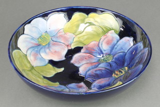 A Walter Moorcroft blue ground bowl decorated with clematis, impressed marks and monogram 10 1/2" 