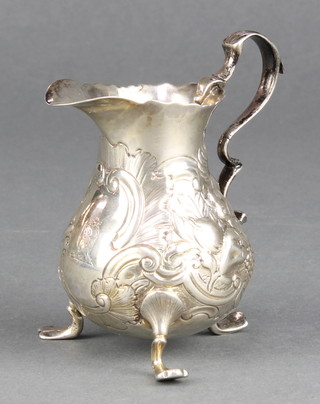 A Georgian repousse silver cream jug with floral and scroll decoration bearing an armorial, rubbed marks, 70 grams 3 1/4" 