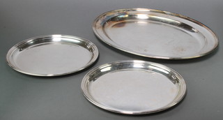A pair of circular silver plated serving trays 12" diam. and an oval ditto 20" 
