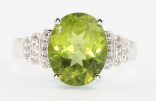 A 14ct white gold oval cut peridot and diamond ring, the centre stone approx 3.8ct, the stepped brilliant cut diamonds approx. 0.25ct, size N 1/2