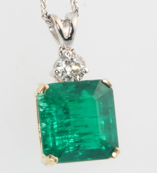 A 18ct yellow gold emerald pendant, the rectangular cut stone approx. 6.41ct surmounted by a brilliant cut diamond approx. 0.31ct hung on a 14ct white gold chain 