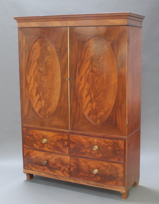 A 19th Century mahogany hall cupboard in the form of a linen press with moulded cornice enclosed by oval panelled doors, the base fitted 2 dummy drawers raised on bracket feet 72"h x 52"w x 19"d 