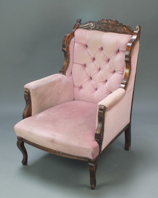 A Victorian carved mahogany show frame armchair upholstered in pink material, raised on cabriole supports