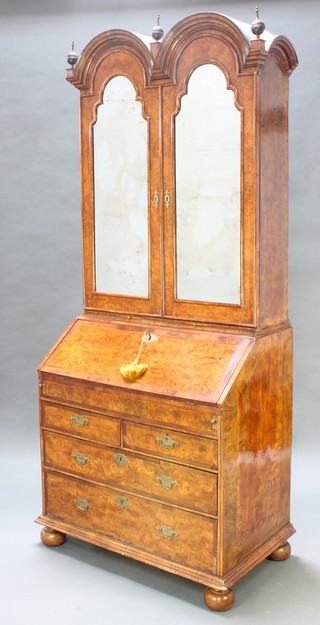 A Queen Anne style figured walnut double domed top bureau bookcase, the interior with pigeon holes and drawer enclosed by arched mirrored doors, the base with 2 candle slides and the crossbanded fall front revealing a well and stepped fitted interior, above 2 short and 2 long drawers with replacement bun feet 90"h x 36"w x 22"d 