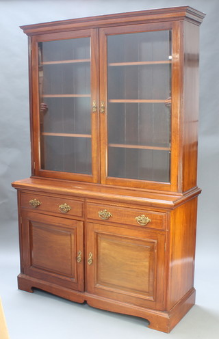 A Victorian walnut bookcase on cabinet, the upper section with moulded cornice, fitted adjustable shelves enclosed by glazed panelled doors, the base fitted 2 drawers above a double cupboard, raised on a platform base 84"h x 54"w x 21"d 